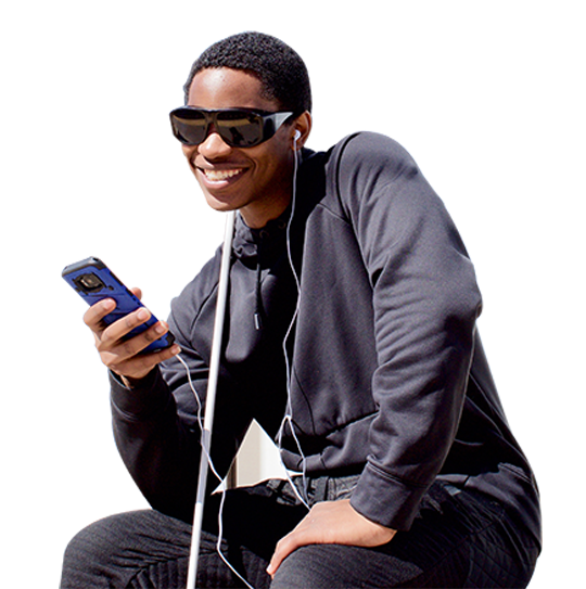 A young man smiles while listening to his phone. His cane rests against his shoulder.